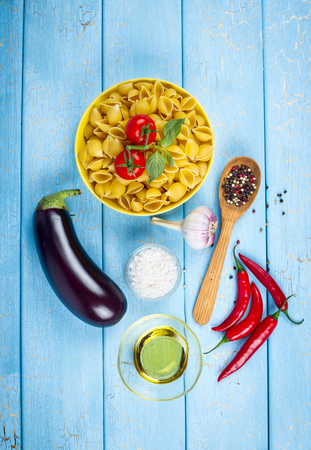 Raw pasta ingredients: eggplant, pepper, garlic, salt and tomato on wooden backgroundの写真素材