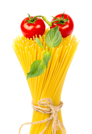 Raw yellow spaghetti pasta with cherry tomatoes and basil leaves isolated on white backgroundの写真素材