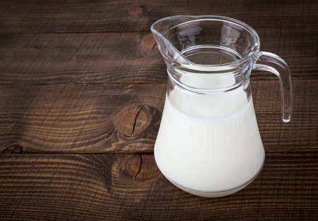 Fresh white milk in glass jar on brown wooden backgroundの写真素材