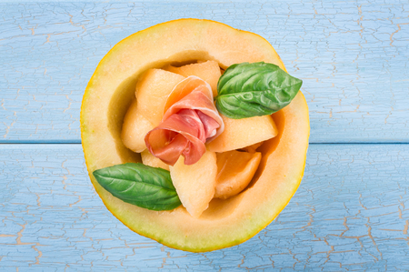 Melon with proscuitto on blue wooden backgroundの写真素材