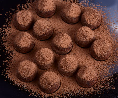 Close up view of chokolate truffles on black plateの写真素材