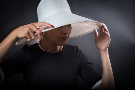Portrait of elegant woman with white hat over black backgroundの写真素材