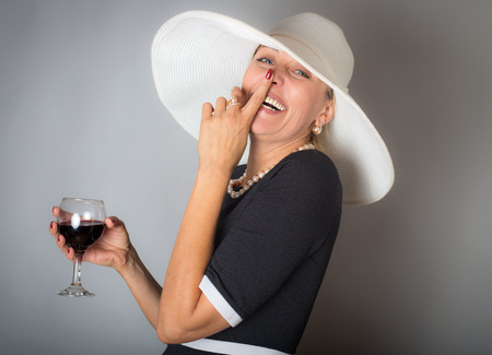 Pretty aged woman with glass of red wineの写真素材