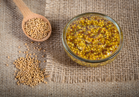 Mustard in glass bowl on burlap backgroundの写真素材
