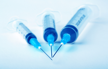 Three plastic syringes on blue backgroundの写真素材
