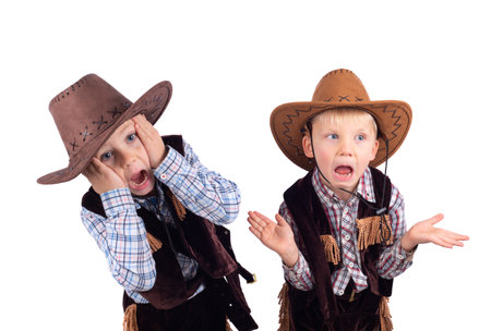 Two little boys dressed in cowboy costume, amazed. Studio shot isolated on white backgroundの写真素材