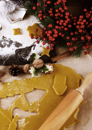 Making christmas gingerbread cookies. Dough with metal cutters, wooden rolling pin, cinnamon, anise, christmas decorationsの写真素材