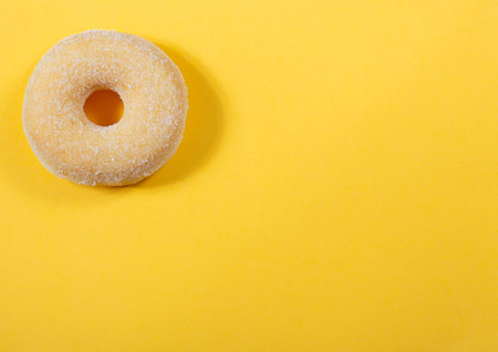 Perfect donut with white sugar on yellow background with copy space. Studio shot, top viewの写真素材