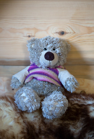 Smiling teddy bear toy sitting on the floor on wooden backgroundの写真素材