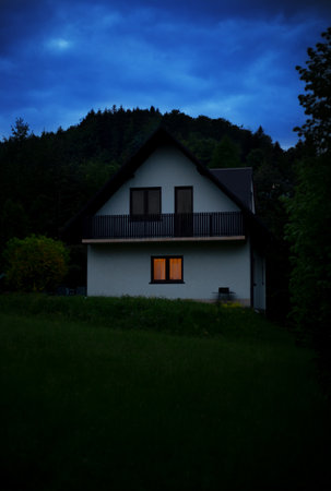 Small house in the forest at night. mountain cottage. Summer landscape with house with glow windowsの写真素材