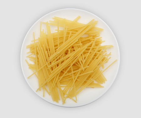 yellow tubelike spaghetti on a white plateの写真素材