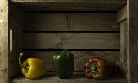 bodegon in a wooden box with three peppersの写真素材