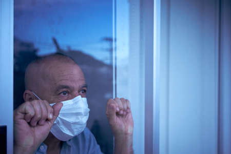 man looking through the glasses in the window of her house, with a look of hppe, taking care of your...