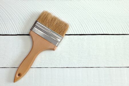 a wide paint brush stands on white painted boards, repair paint brushes, paint stains and smudges...