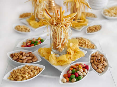 a snack for beer is beautifully served on the table: cheese, chips, peanuts, pistachios. Side view