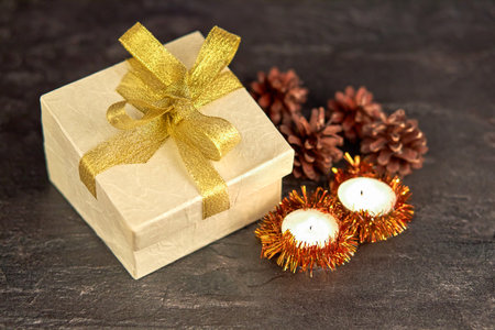 Vintage Christmas background with Christmas gift, pine cones, candles on a dark background. Shallow...