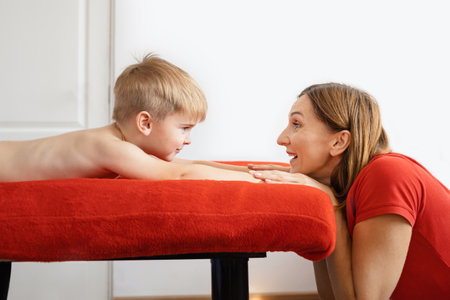 Mom and 5 year old son relax and play together in bed on weekends, lazy morning, warm and cozy scene. red and white colorsの写真素材
