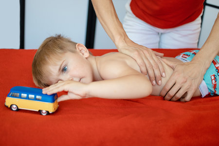 little blond kid in the spa at the massage reception playing with toysの写真素材