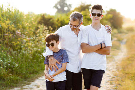 Happy father in nature with his two sons chatting and having fun. Family, father and two sonsの写真素材