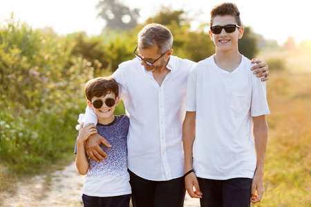 Happy father in nature with his two sons chatting and having fun. Family, father and two sonsの写真素材