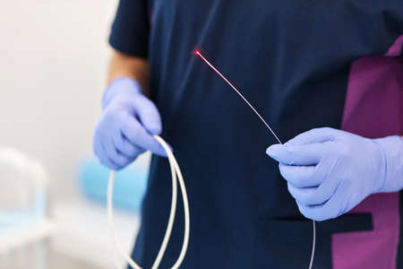 close-up of a doctors hands are holding a laser for the treatment of varicose veins.