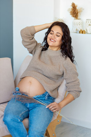 Home cozy portrait of a pregnant woman in a warm cashmere sweater resting at home.の写真素材