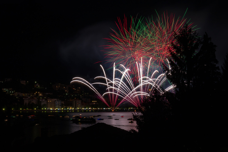 panoramic view of omegna during a fireworks display during the San Vito festivalの写真素材