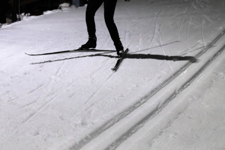 Person Engages in Cross-Country Nighttime Skiing on Snowy Tracksの写真素材