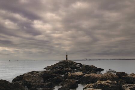 Seascape with a rocky path to a light house in Roses beach in Costa Brava in Cataloniaの写真素材