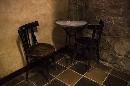 Two chairs and a table with a domino game and a bottle in an antique pub