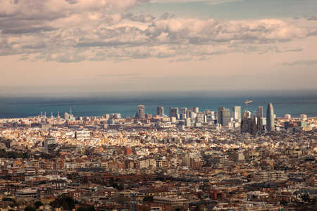 Barcelona cityscape and Mediterranean sea viewed from above under a cloudy sky