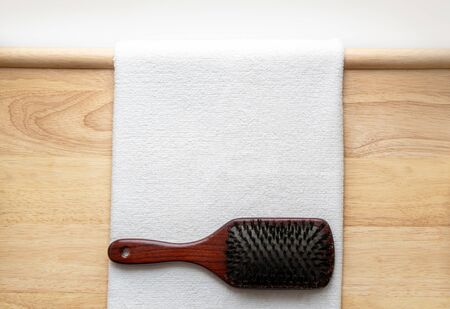 Wooden hair brush on wooden background next to a white towelの写真素材