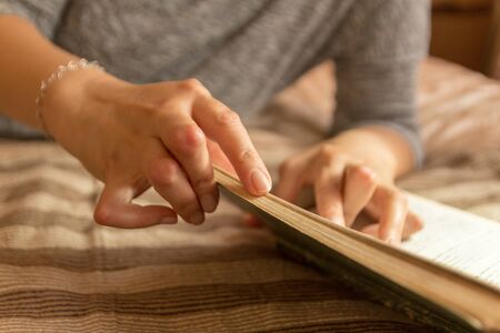 Young woman having rheumatoid is reading a book. Hands and legs are deformed. She feels pain. Selective focus.の写真素材