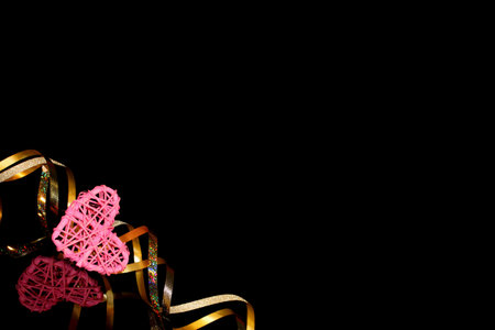 beautiful festive background, golden ribbon on a black background with a pink heartの写真素材