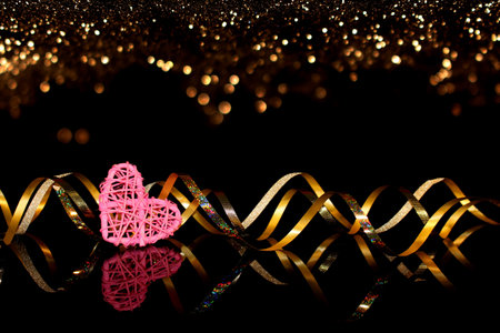 beautiful festive background, golden ribbon on a black background with a pink heartの写真素材