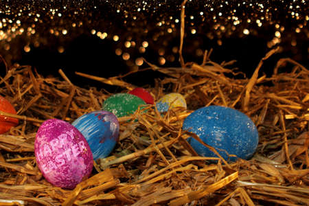 beautiful colorful Easter eggs lie on the straw with a shiny background