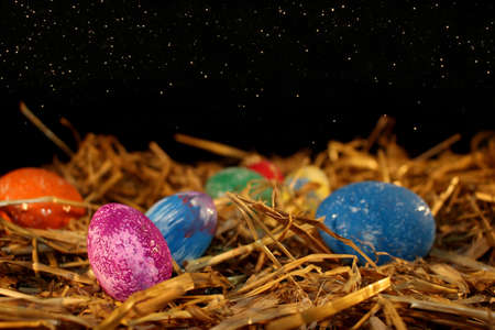 beautiful colorful Easter eggs lie on the straw with a shiny background