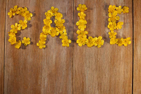 beautiful inscription sale, laid out of buttercup flowers on a wooden backgroundの写真素材
