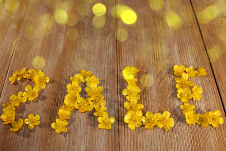 beautiful inscription sale, laid out of buttercup flowers on a wooden backgroundの写真素材