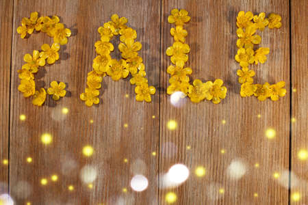 beautiful inscription sale, laid out of buttercup flowers on a wooden backgroundの写真素材