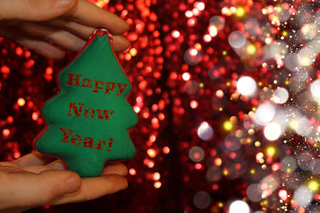 beautiful Christmas tree is lying on his hands, on a shiny backgroundの写真素材