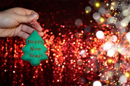 beautiful Christmas tree is lying on his hands, on a shiny backgroundの写真素材