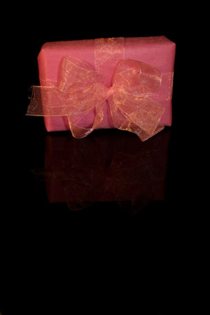 A beautiful pink gift with a bow on a black backgroundの写真素材