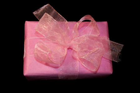 A beautiful pink gift with a bow on a black backgroundの写真素材