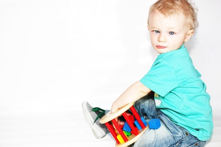 Cute adorable blonde newborn baby with blue eyes playing with constructionsの写真素材