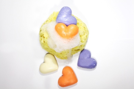 A yellow sponge in soap bubbles with some soap heartsの写真素材