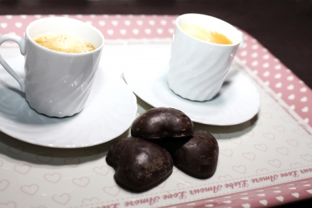 Two cups of coffe on a tray with some chocolate treatsの写真素材