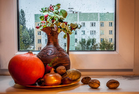 still life with a pumpkin and a pitcher on a window in a rainy dayの写真素材