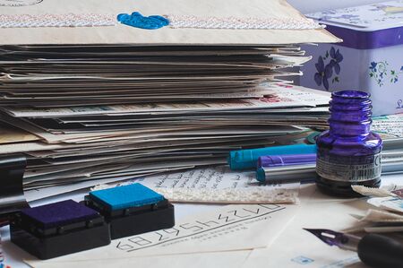 Postcrossing still life. Pile of postcards, ink bottle, fountain pen, colorful pens around.のeditorial素材
