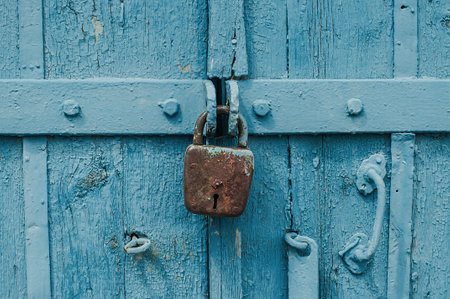 Old iron barn lock on a blue wooden doors.の写真素材